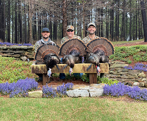 Three hunters with harvested turkeys at the lodge